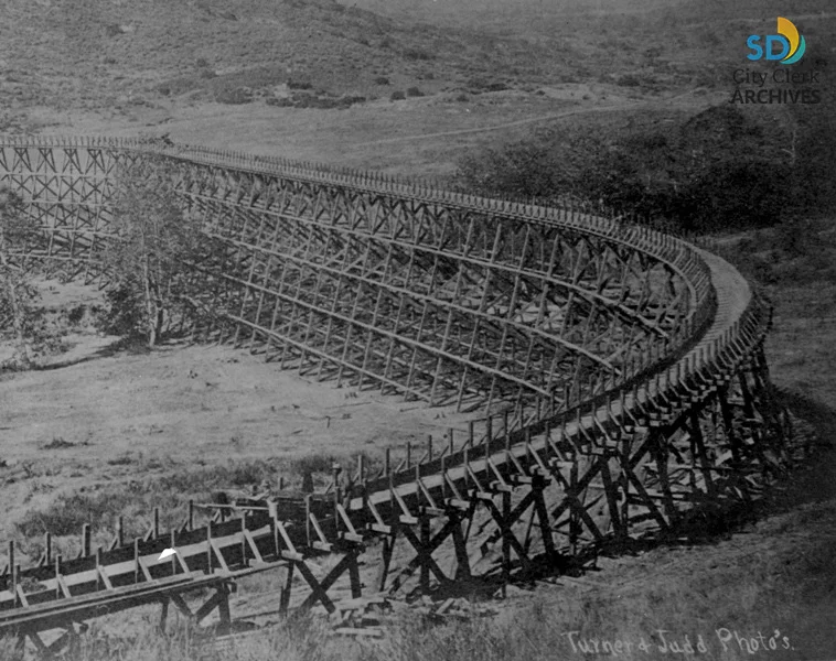 Curved wooden trestle bridge on a railway track in a rural landscape.
