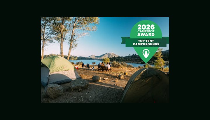 A scenic campsite by a lake with tents, picnic area, and a 2026 Campspot Award for top tent campgrounds displayed.