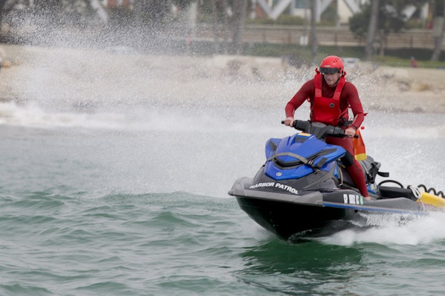 A person riding a jet ski marked "Harbor Patrol" on water, creating a splash.
