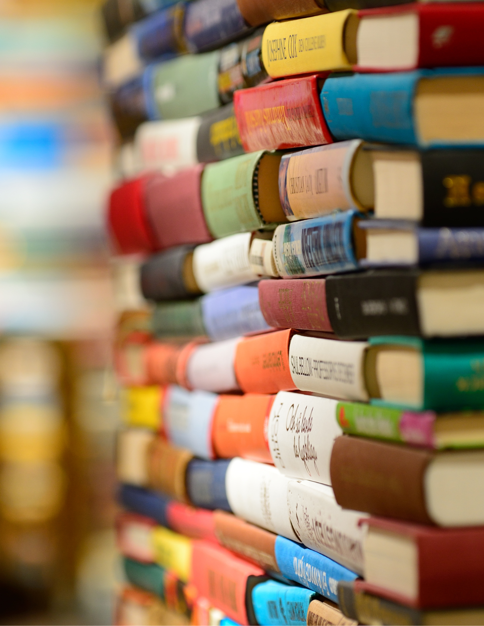 A close-up view of a stack of colorful books with various titles and bindings, creating a vibrant display of literature.