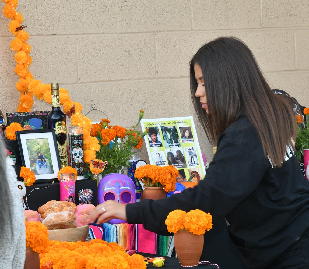 Young girl placing an offering on the 'Ofrenda' table