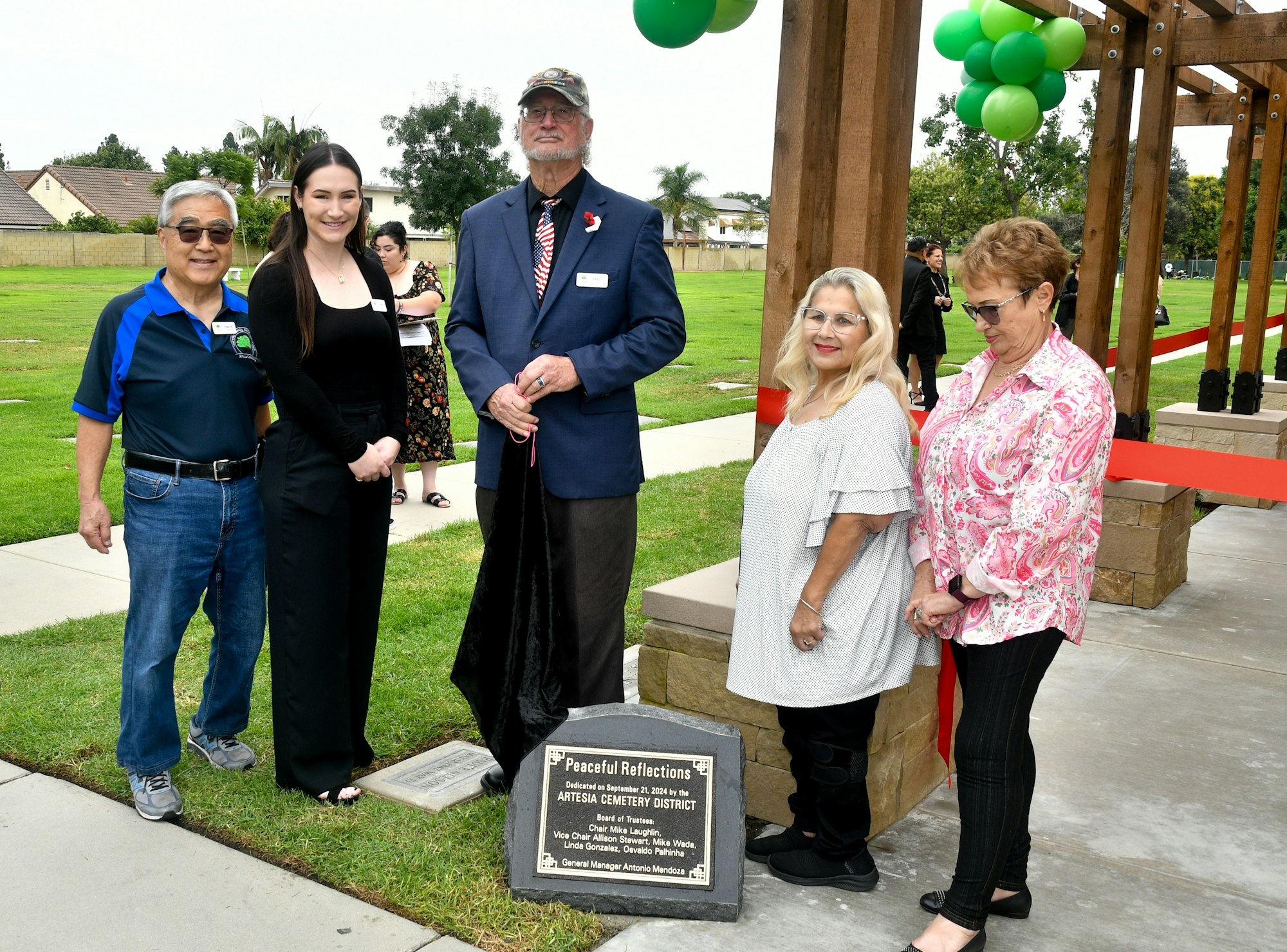 Group of people at an outdoor event, standing next to a commemorative plaque.