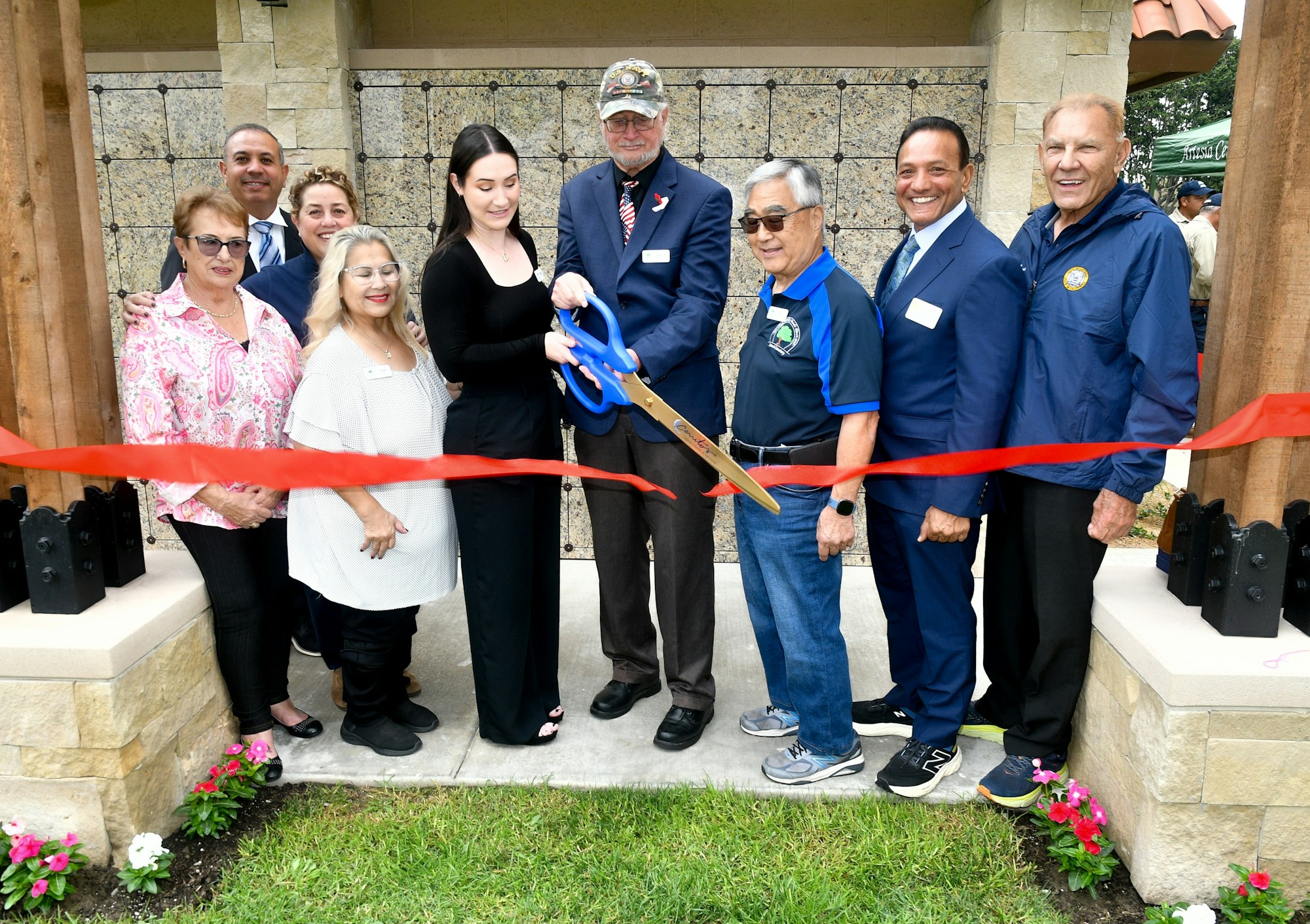 Group of people participating in a ribbon-cutting ceremony, likely opening a new facility or celebrating an event.