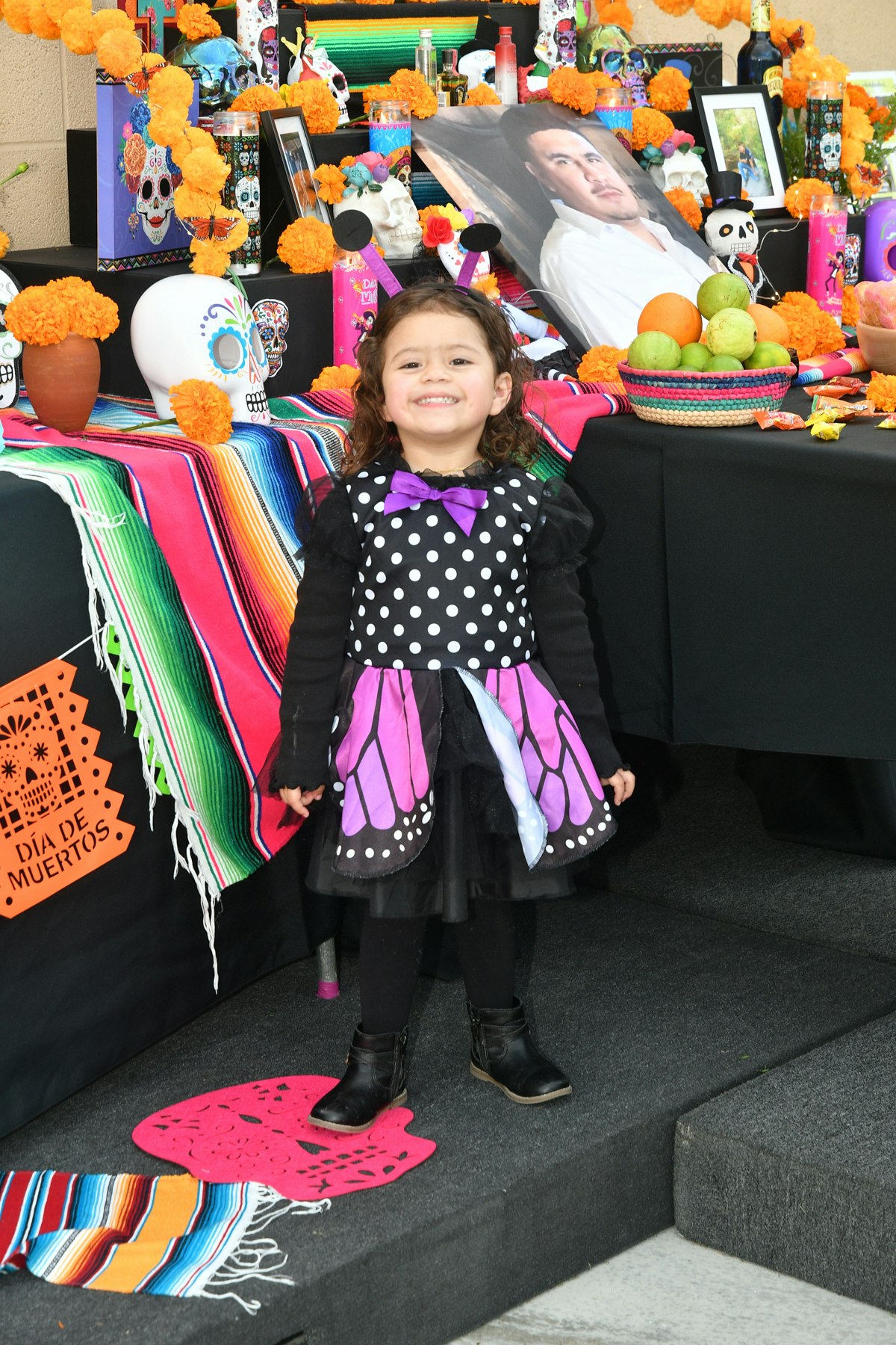 Small child smiling in front of the 'Ofrenda' table