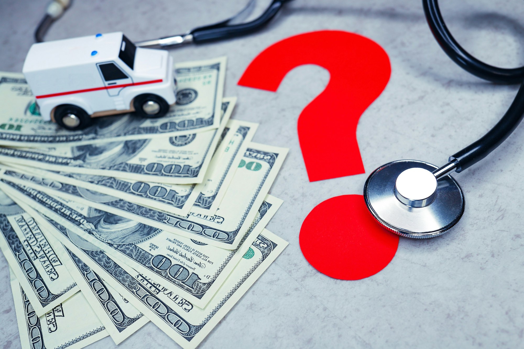 $100 bills, stethoscope, rescue squad or ambulance and red question mark