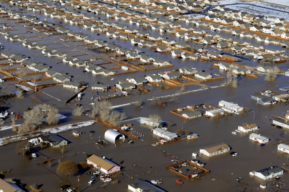 A residential area flooded, with many houses and streets submerged under water.