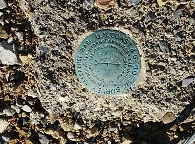The image shows a U.S. Coast & Geodetic Survey benchmark disk set in concrete, used for surveying.