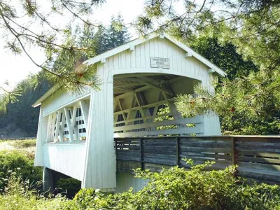 A charming white covered bridge surrounded by greenery and trees, showcasing a peaceful rural setting.