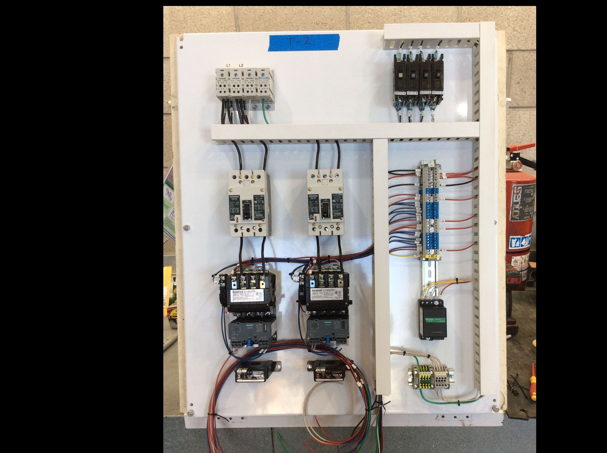 The image shows a control panel with electrical components including relays, contactors, and wiring.