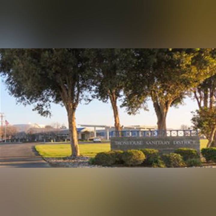 The image shows the entrance to the Trentwood Sanitary District, featuring trees and a sign in a landscaped area.