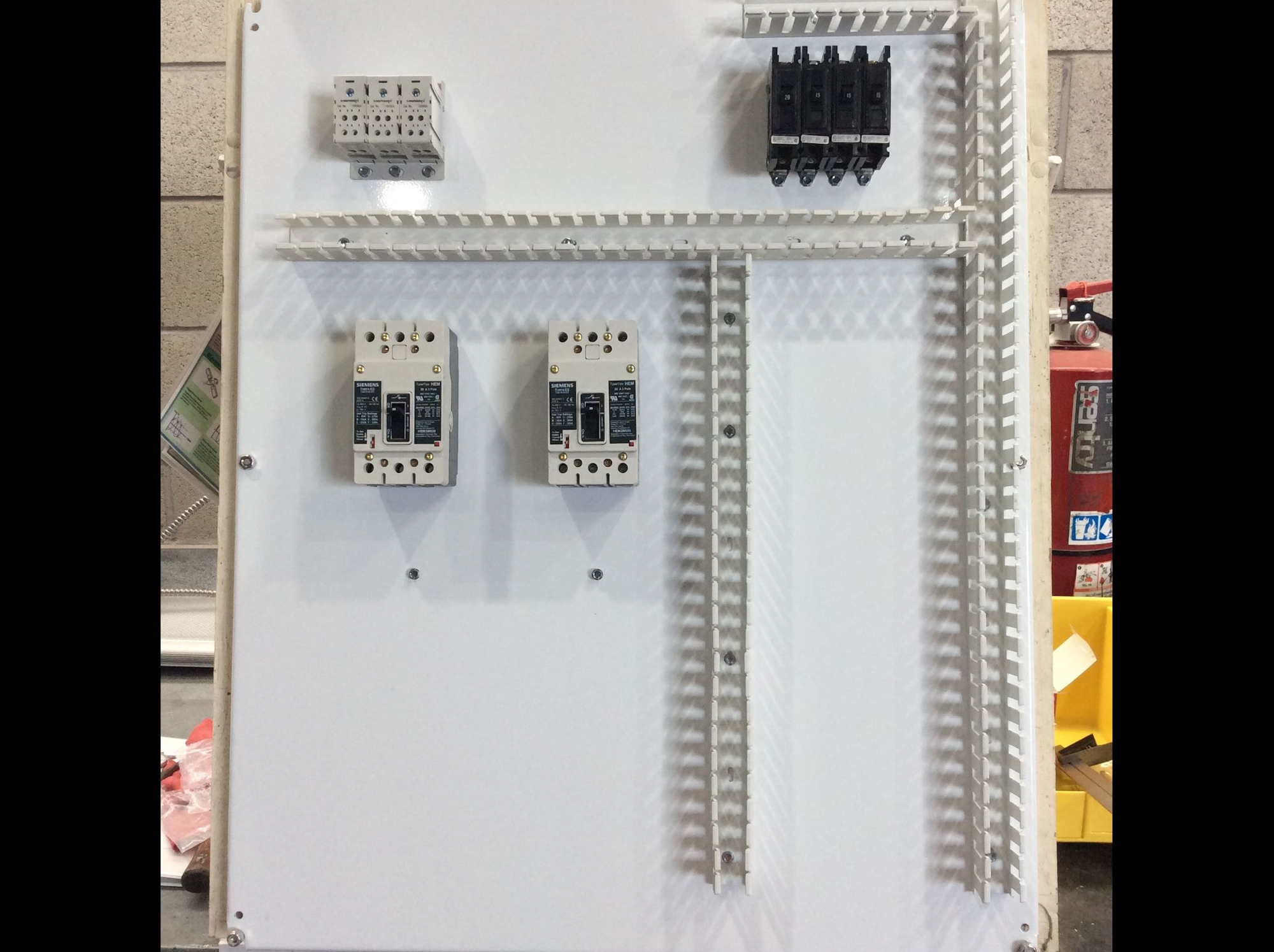 The image shows a mounting panel with various electrical components, including circuit breakers and relay holders.