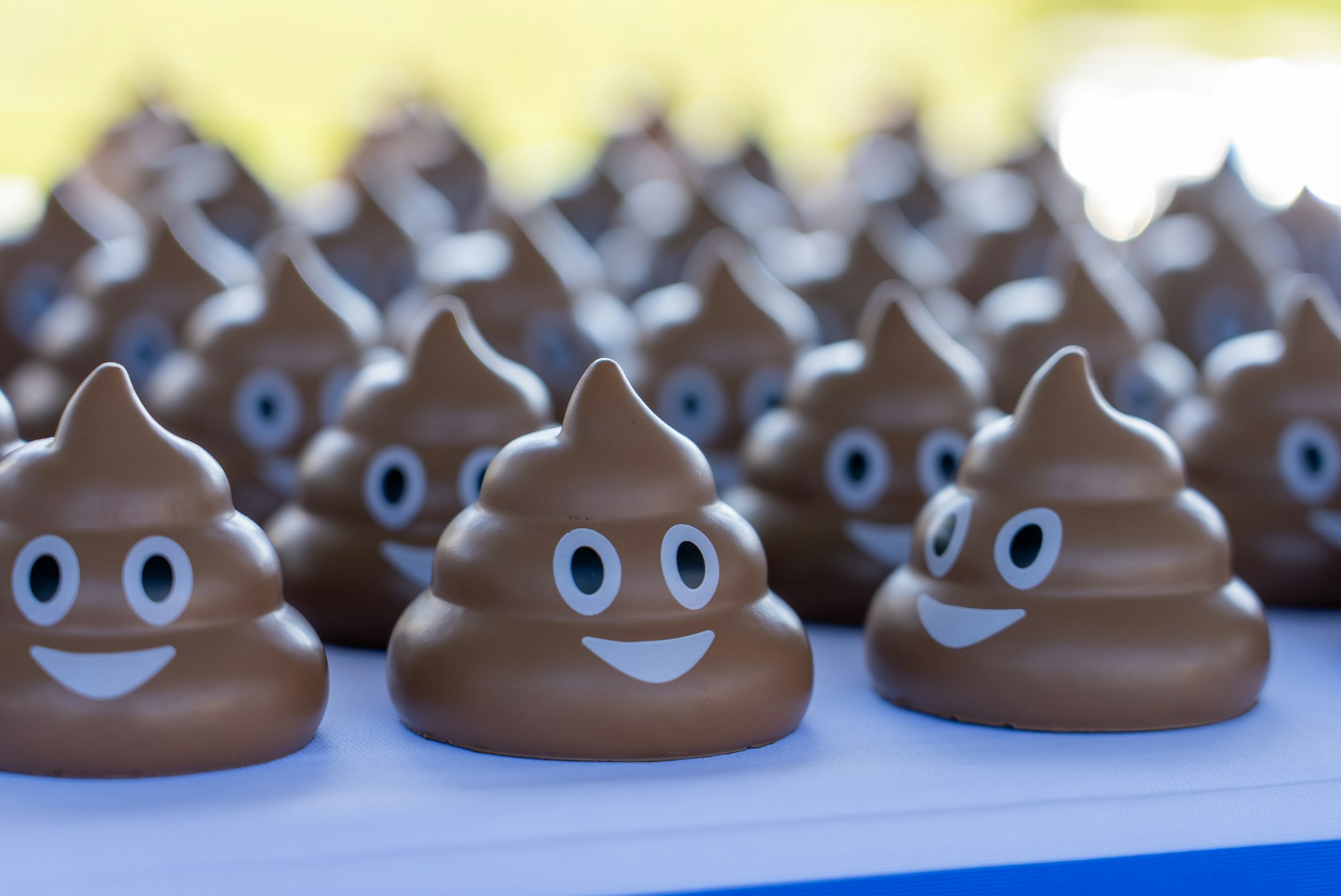 The image features a collection of cute, cartoonish poop emojis, all smiling and arranged in a row.