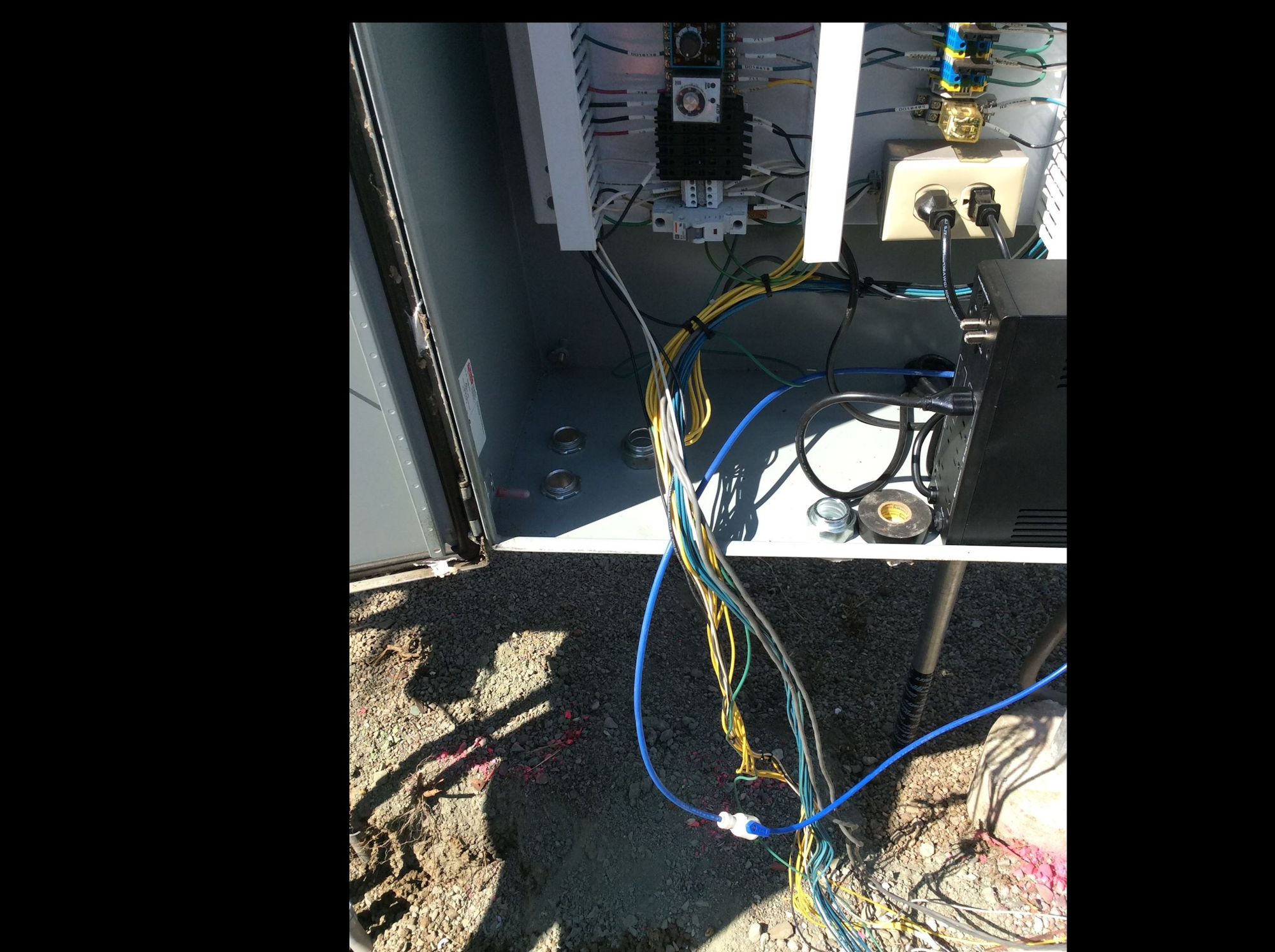 An open electrical cabinet with various wires connected to a circuit board and power components inside.