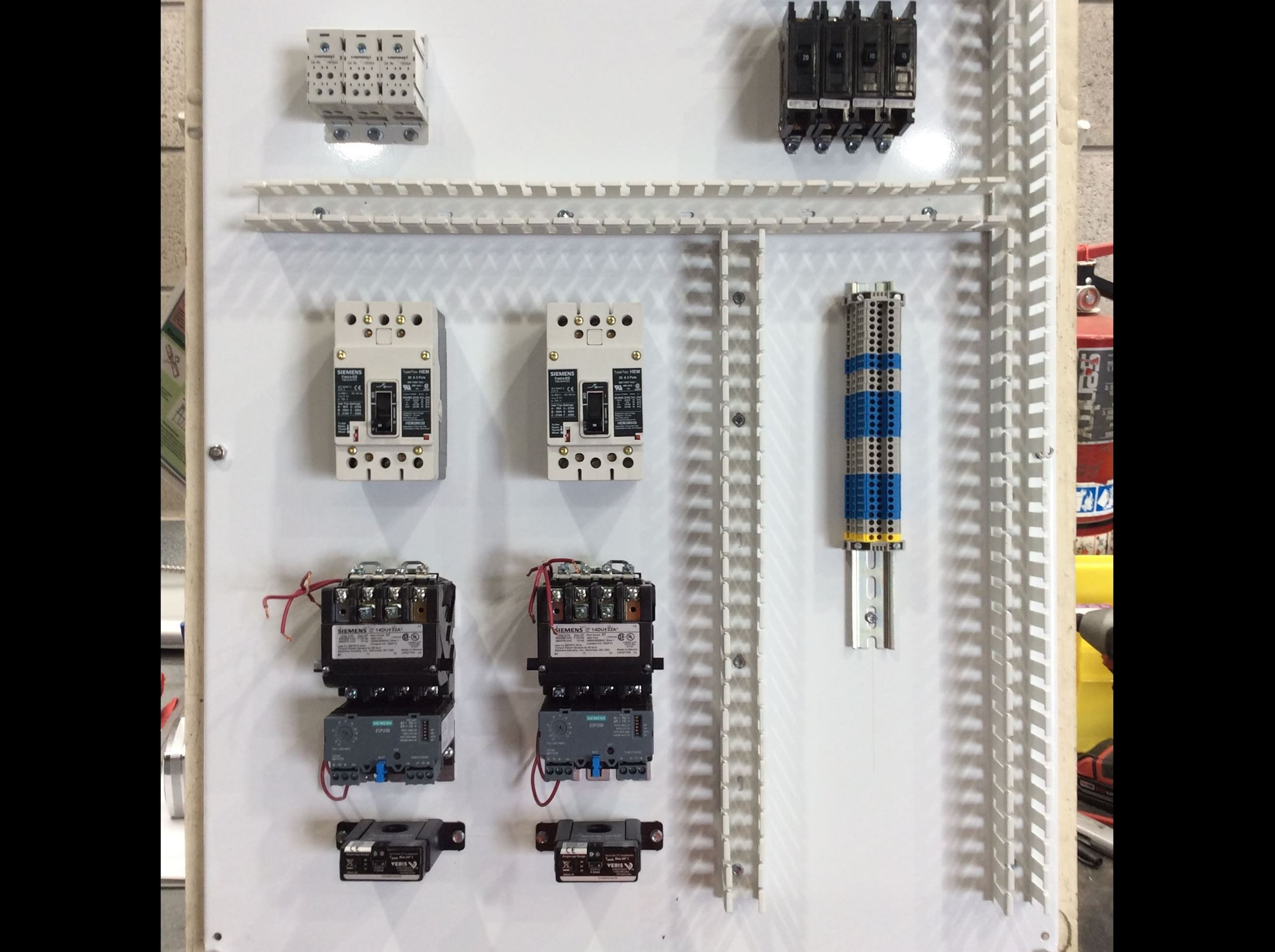 The image shows a panel with various electrical components, including relays, contactors, and circuit breakers arranged on a white background.