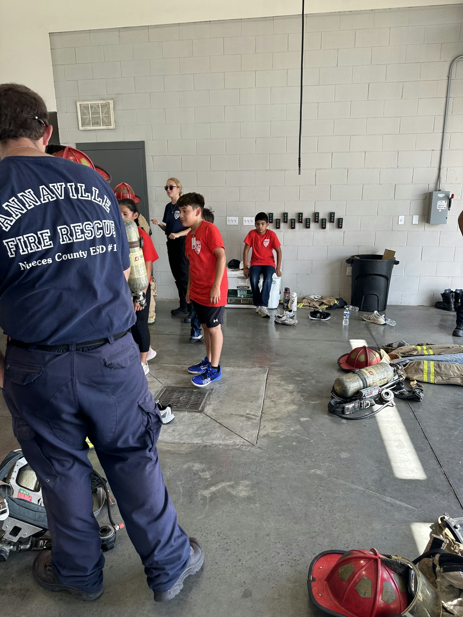 People, including children, in a fire station with gear and helmets, titled "Annaville Fire Rescue."