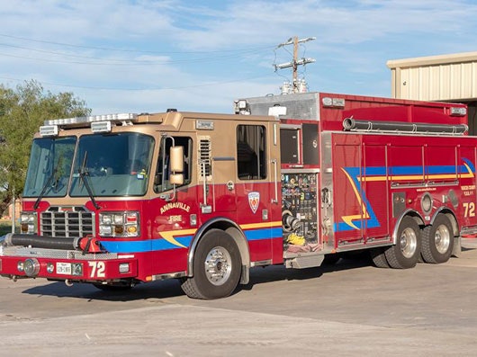 A red and tan fire truck parked outdoors on a sunny day.