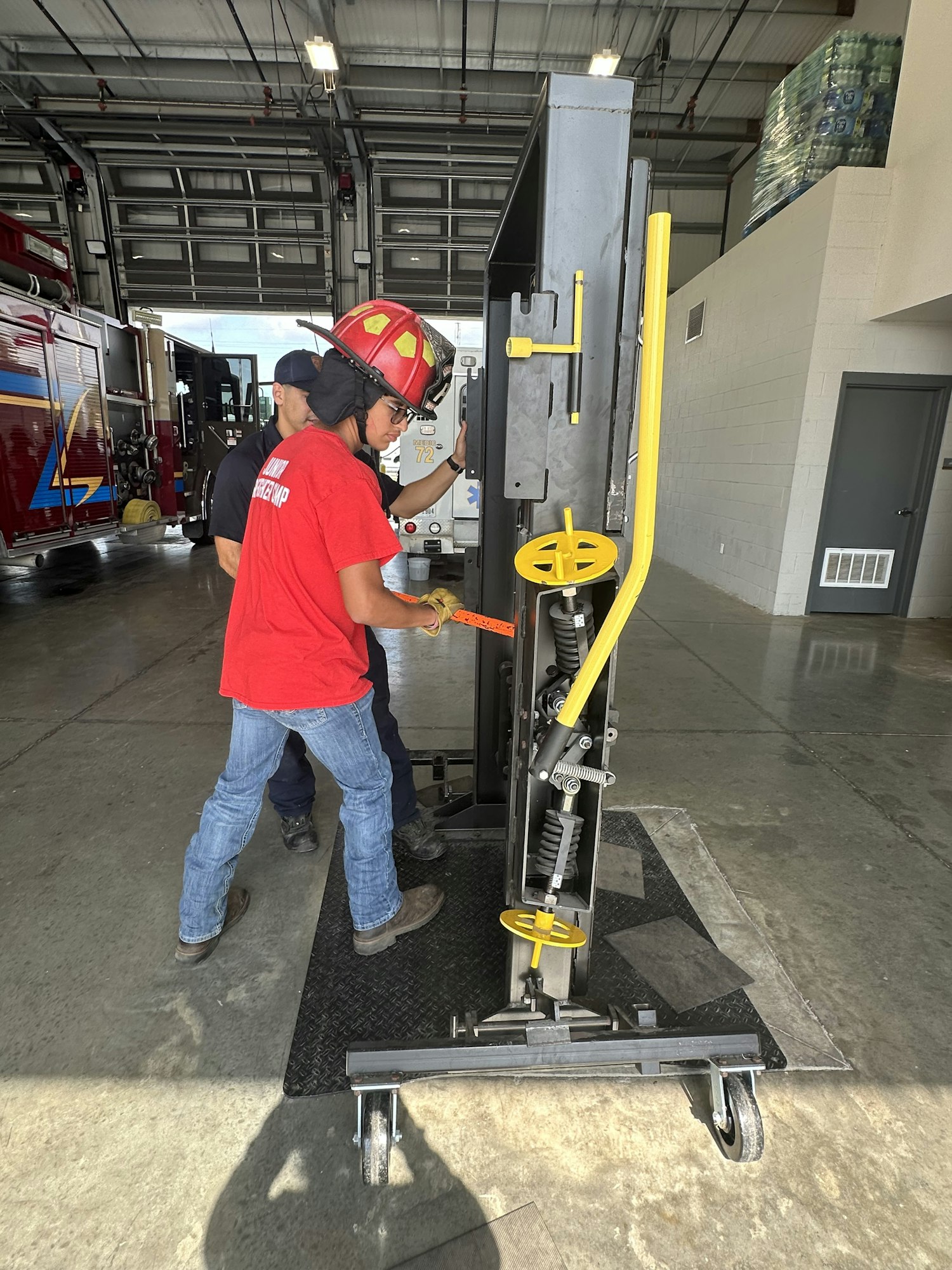 A person in a firefighter’s uniform adjusts a large mechanical device in a fire station.