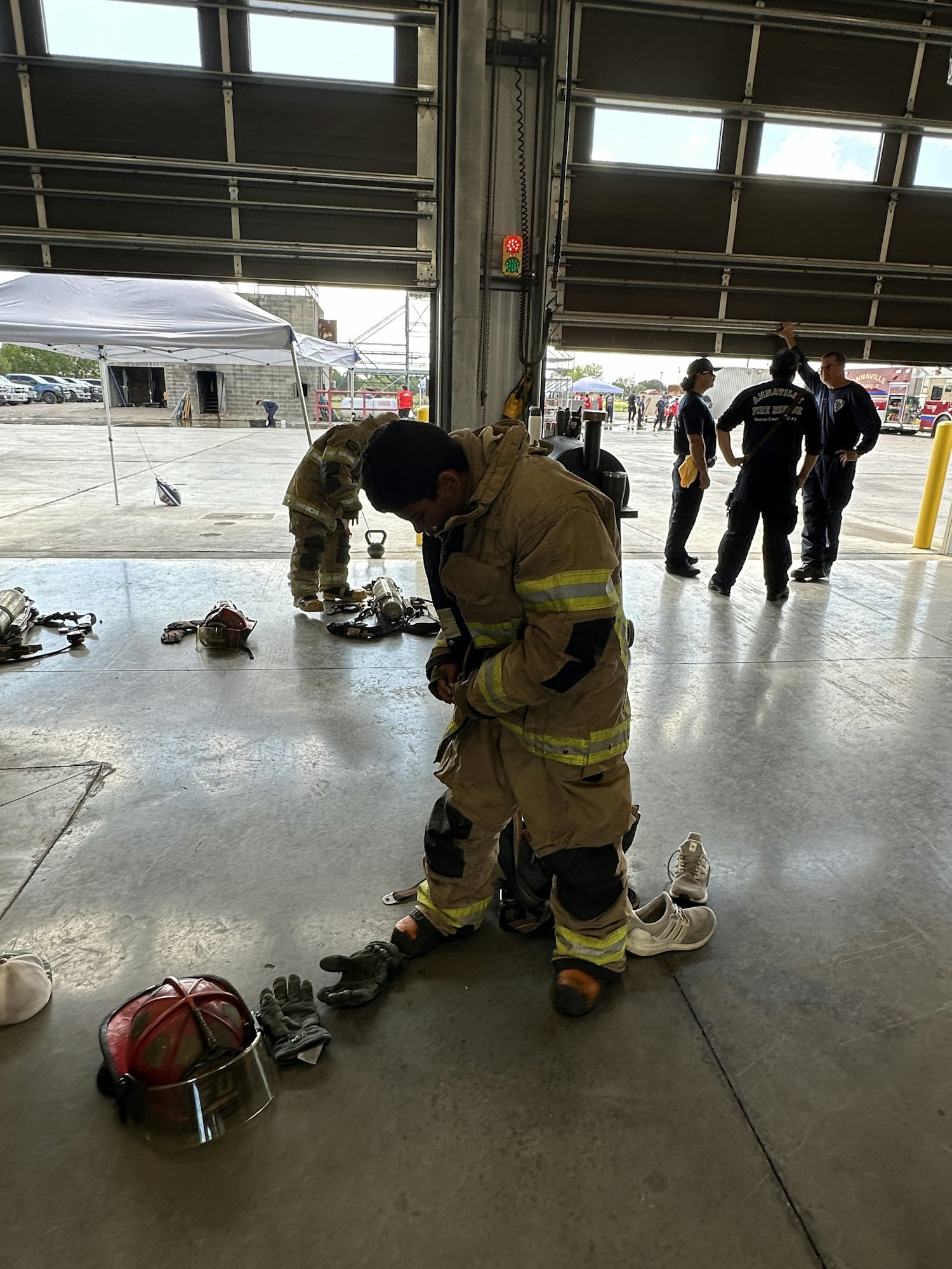 Firefighters in gear inside a garage, adjusting equipment and preparing for action.