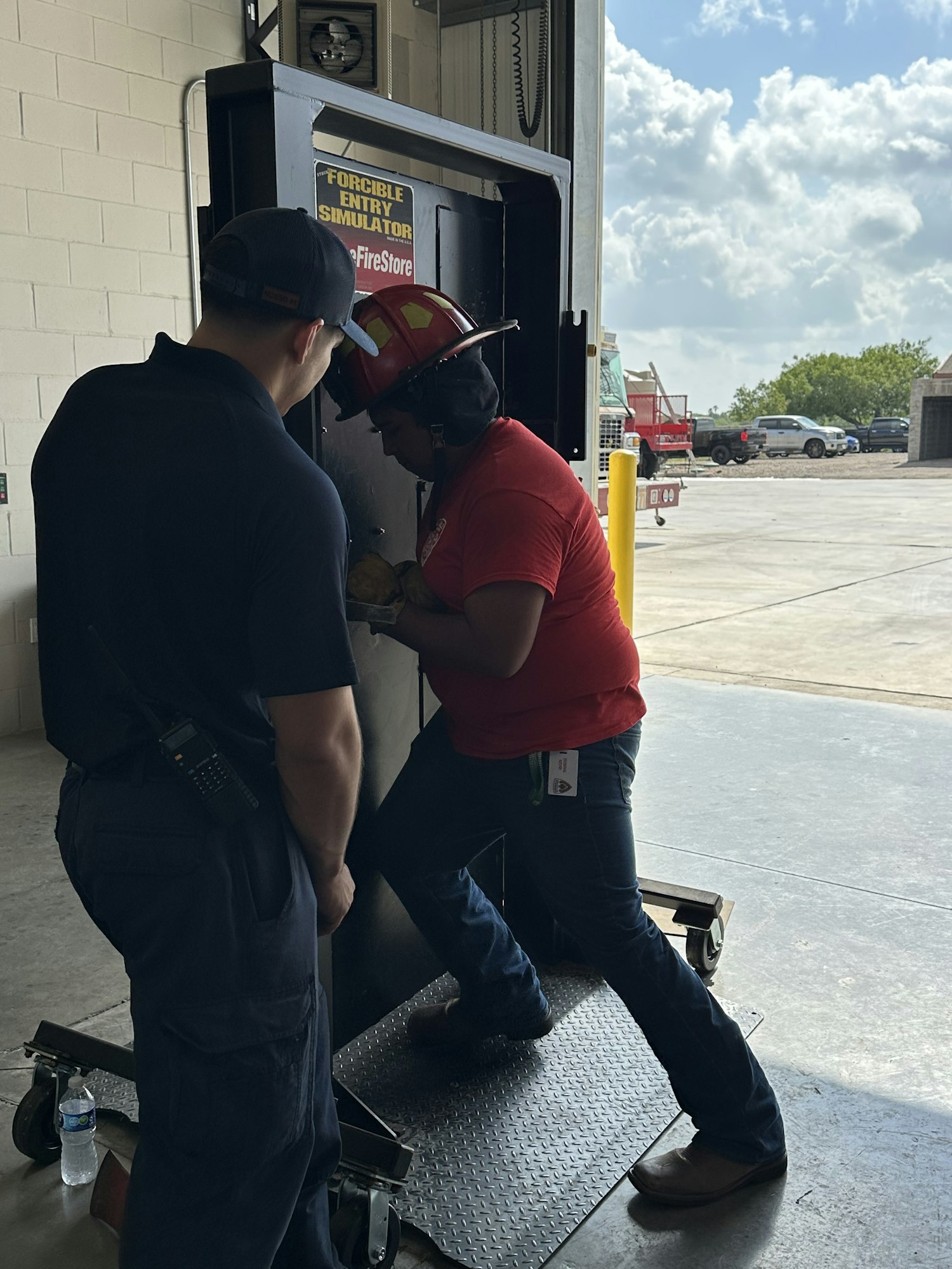 Two people in uniform practicing on a forcible entry simulator.