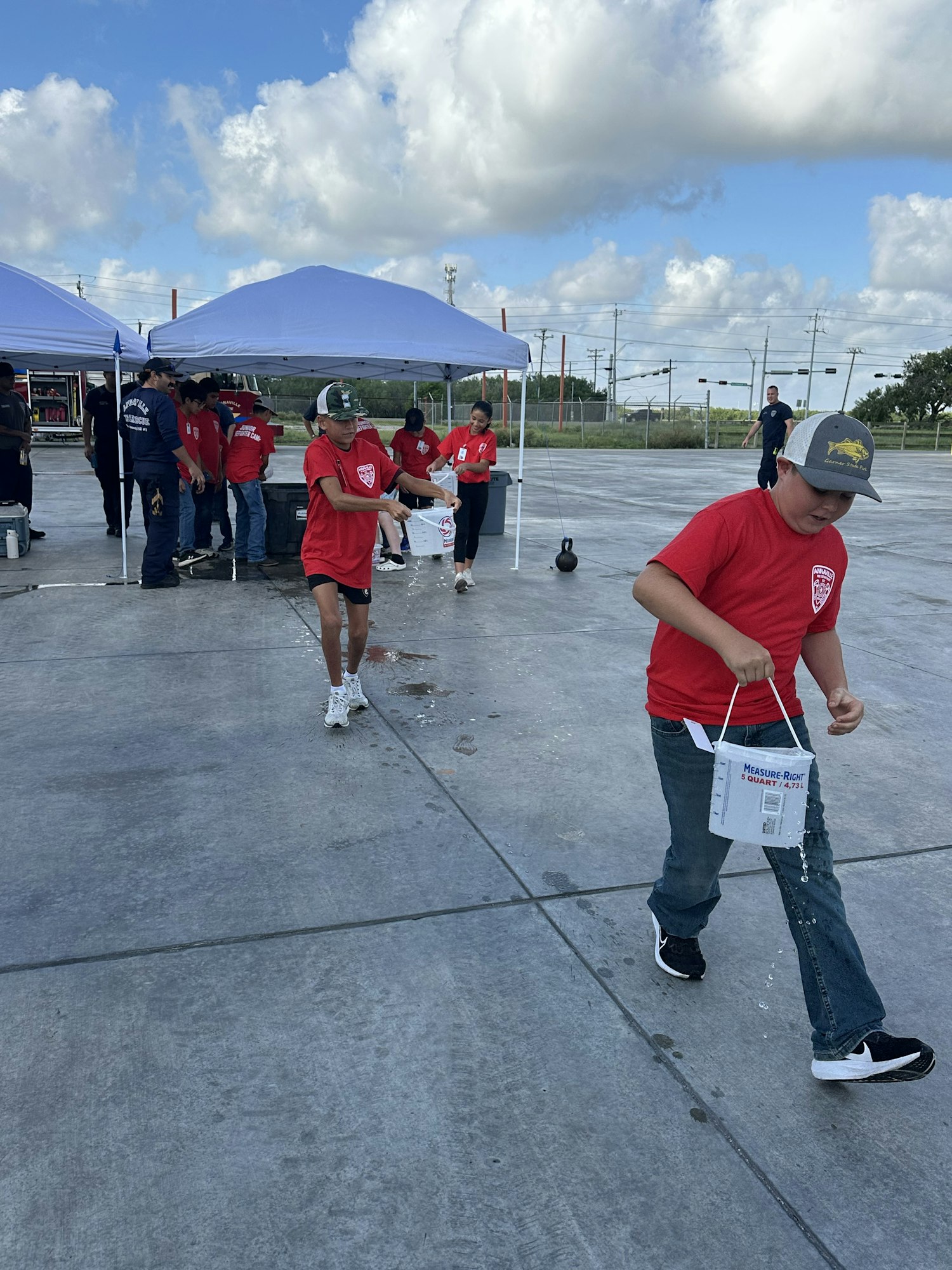 A group of people in red shirts participating in an outdoor activity near tents.