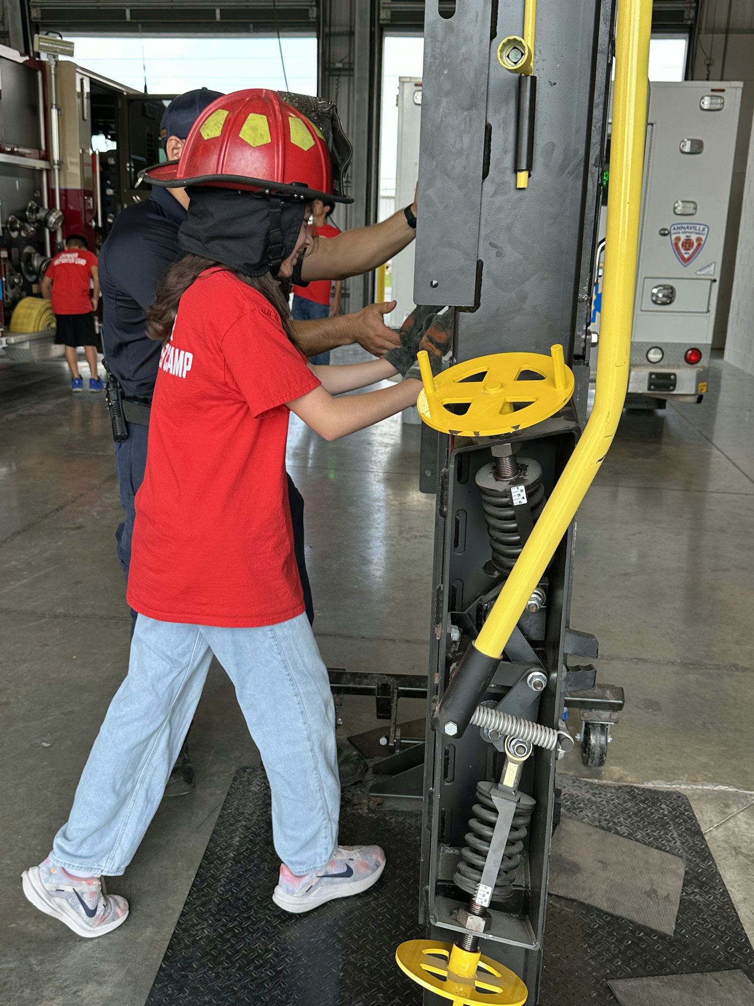 Two people in safety gear work on a metal structure inside a garage.