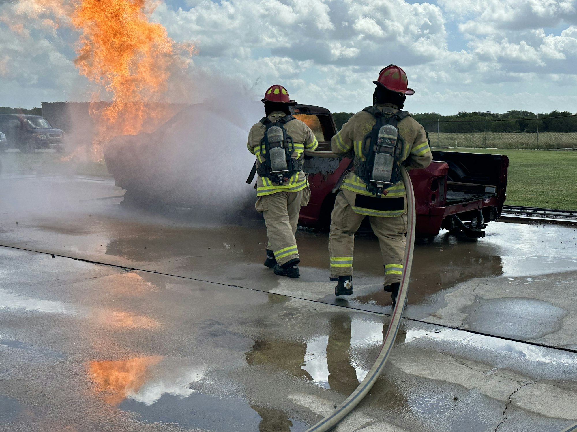 May contain: helmet, person, clothing, footwear, shoe, extinguishing fire, fire, car, transportation, and vehicle
