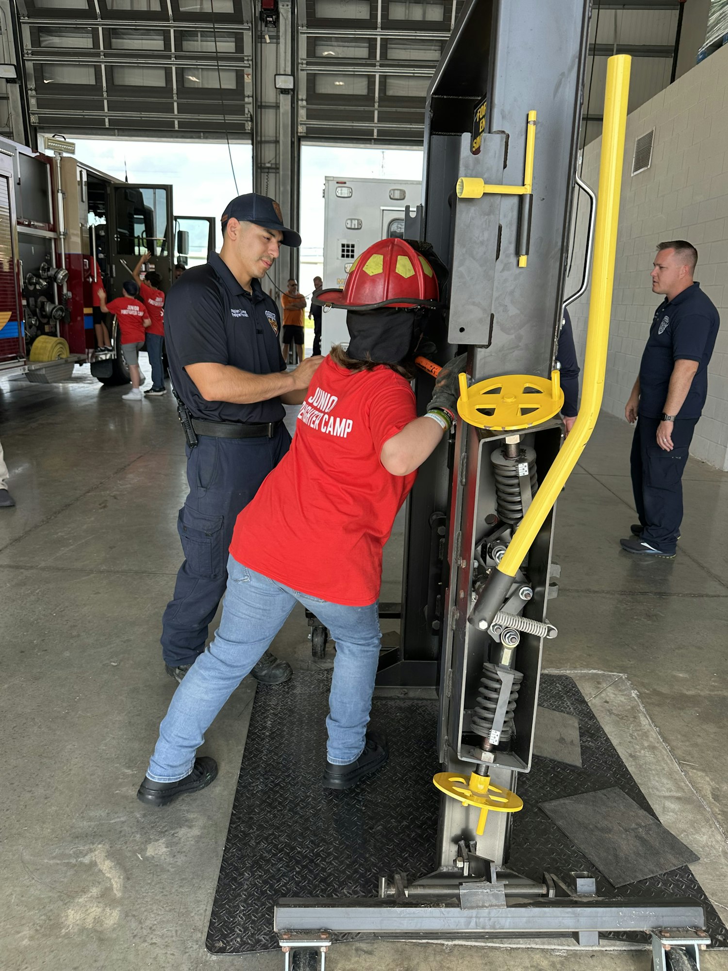 Firefighters assisting with equipment alongside a fire engine in a garage.