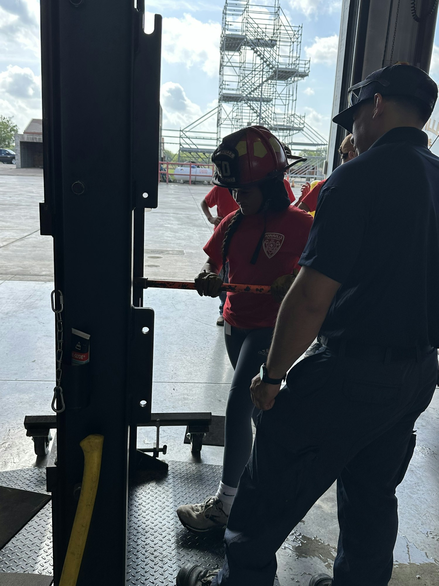 Two people, one in firefighting gear, working with equipment inside a building.