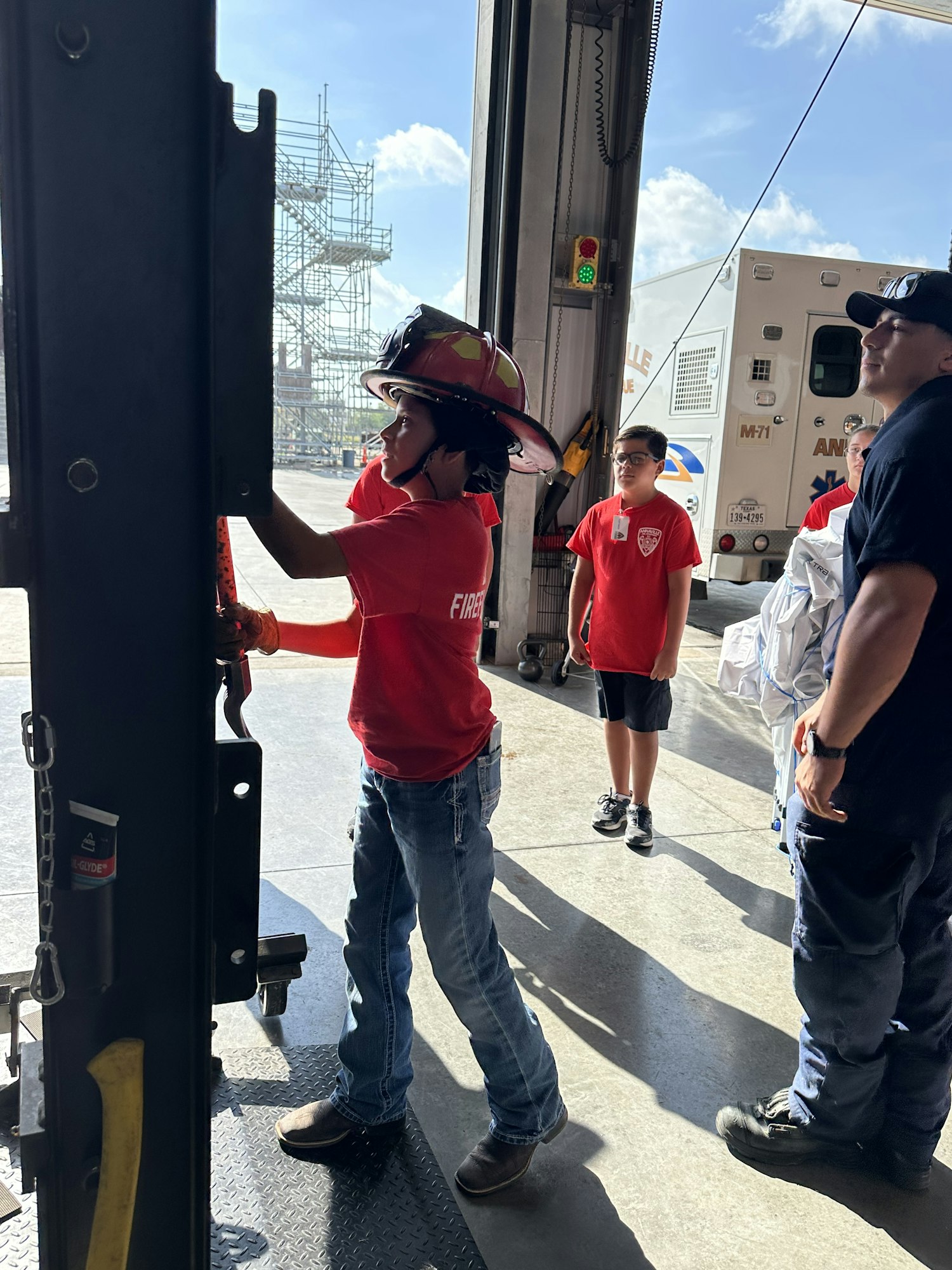 People in red shirts and safety gear are at a garage with an ambulance.