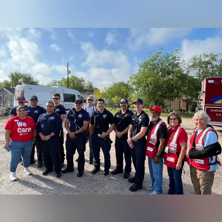A group of first responders and volunteers in front of emergency vehicles, showcasing community support and teamwork.