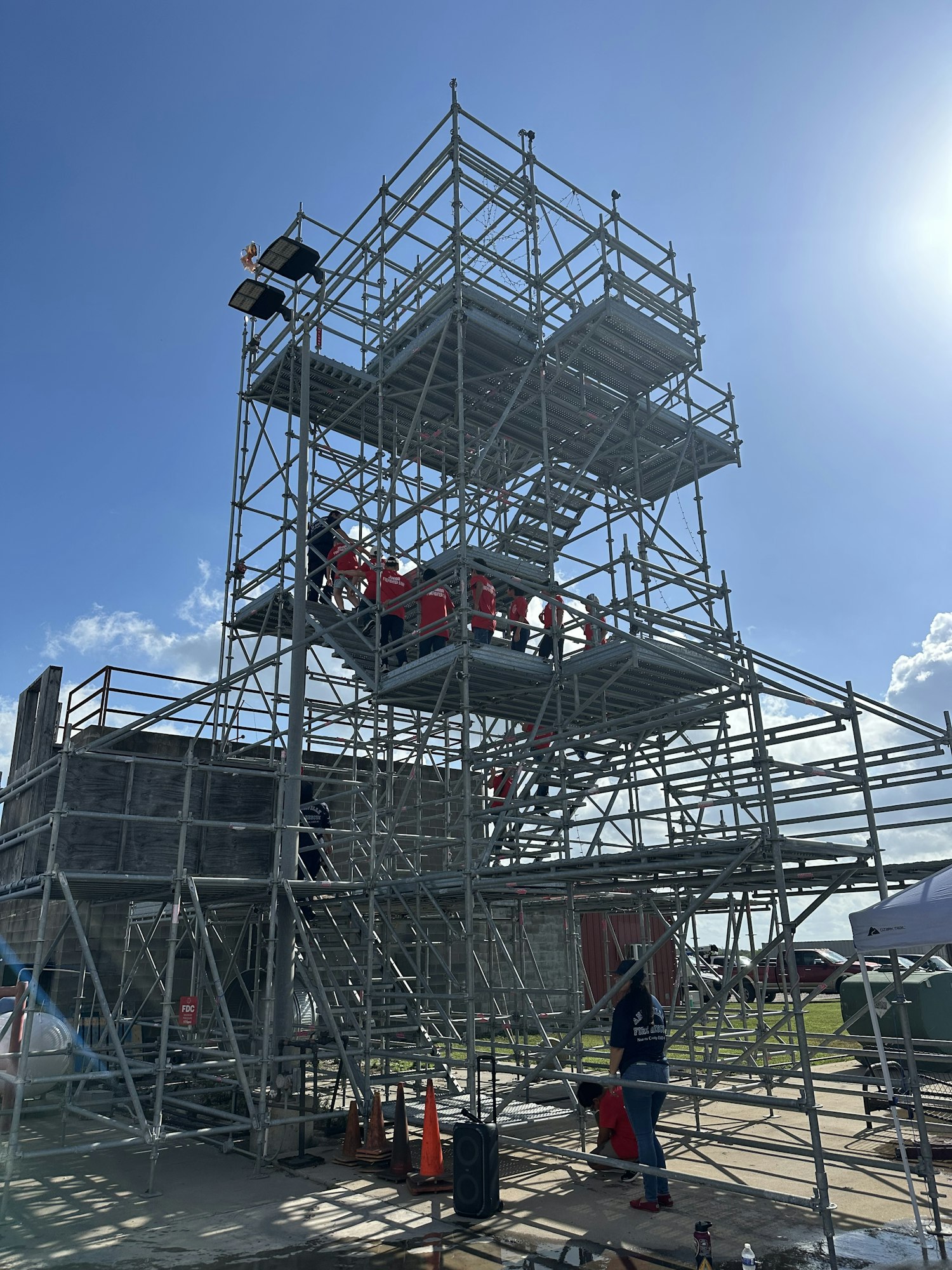 A large metal structure with scaffolding under a bright blue sky.