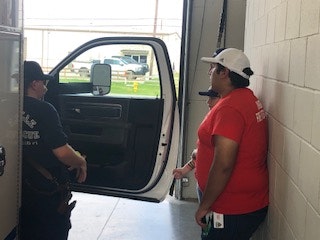 Two people beside an open vehicle door inside a garage-like space.