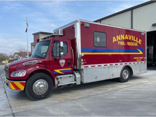 Red fire rescue vehicle labeled "ANNAVILLE FIRE RESCUE" parked outside a building.