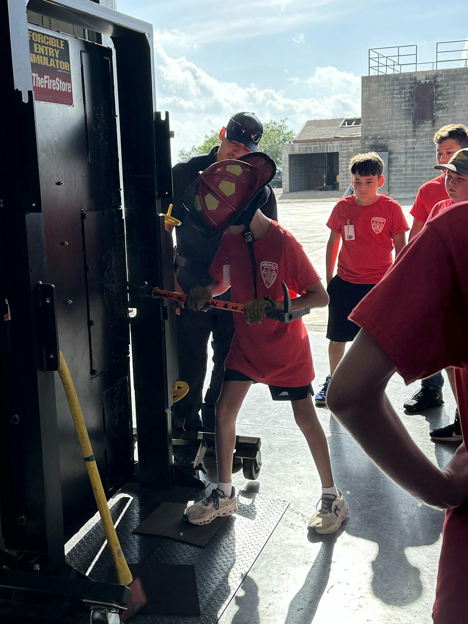 People in red shirts using a forcible entry simulator.