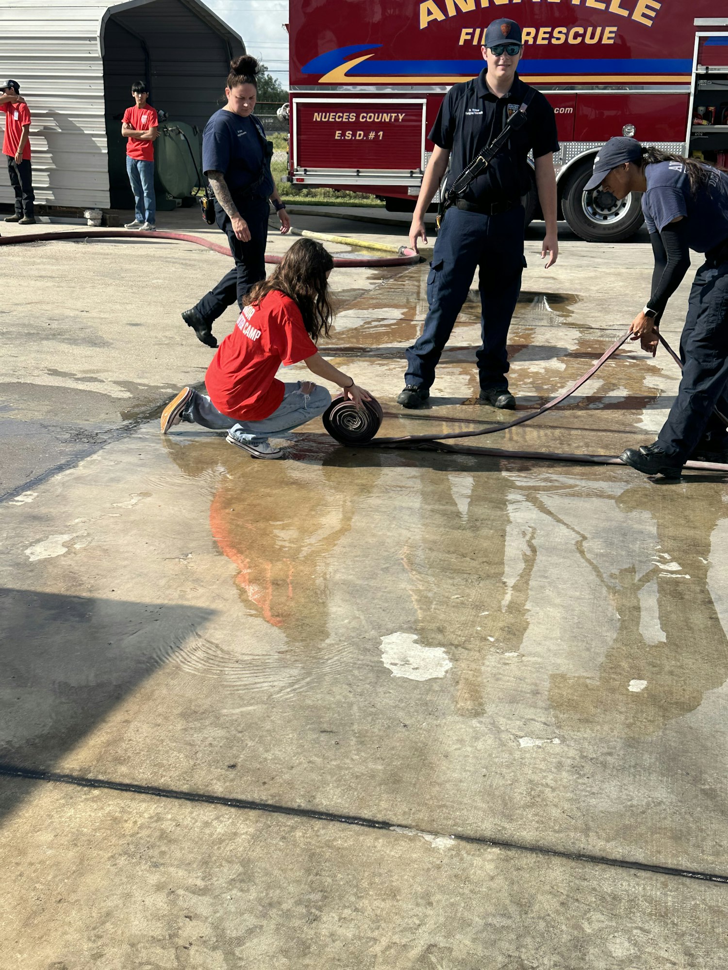 People are interacting with firefighting equipment near a fire rescue truck.