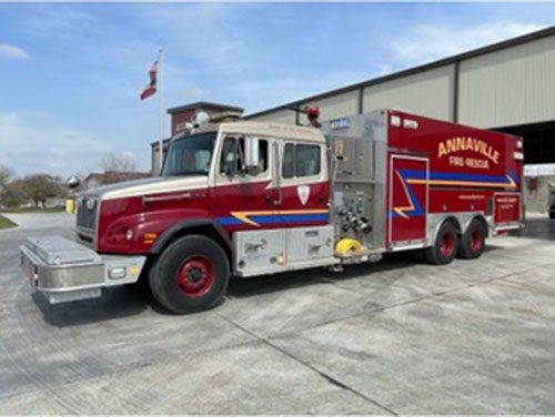 A red fire truck labeled "Annaville Fire Rescue" is parked outside a fire station.