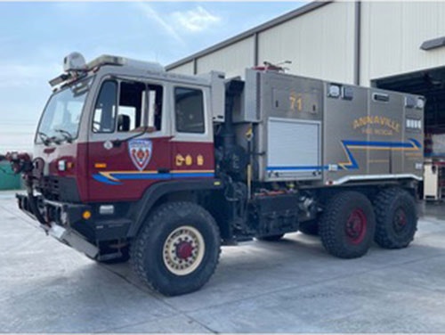 A specialized fire truck with "ANNAVILLE FIRE RESCUE" on its side, parked outside a building.