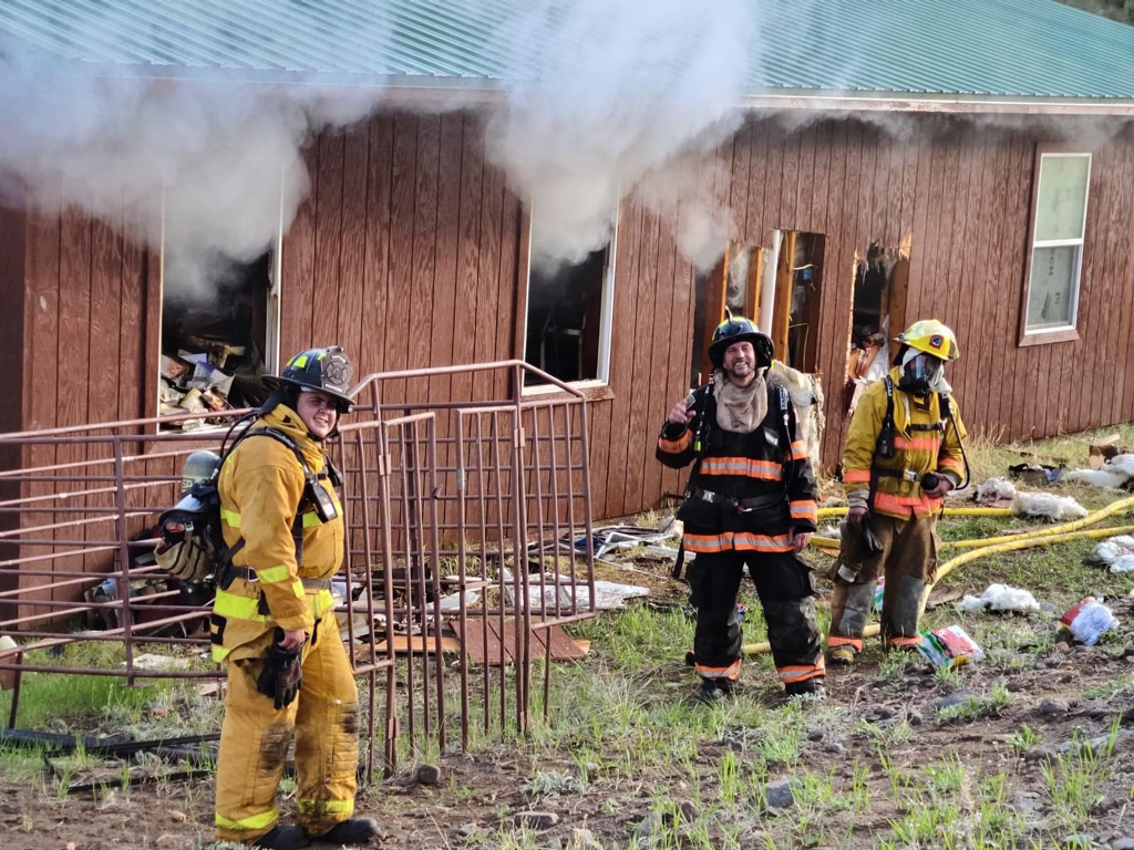 contains firefighter standing outside a building with smoke coming from the windows