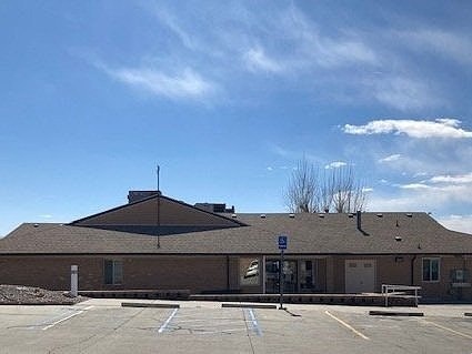 A building with a parking lot, under a clear blue sky with a few clouds.