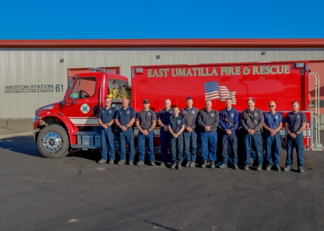 Firefighters standing in front of a fire engine at the East Umatilla Fire & Rescue station.