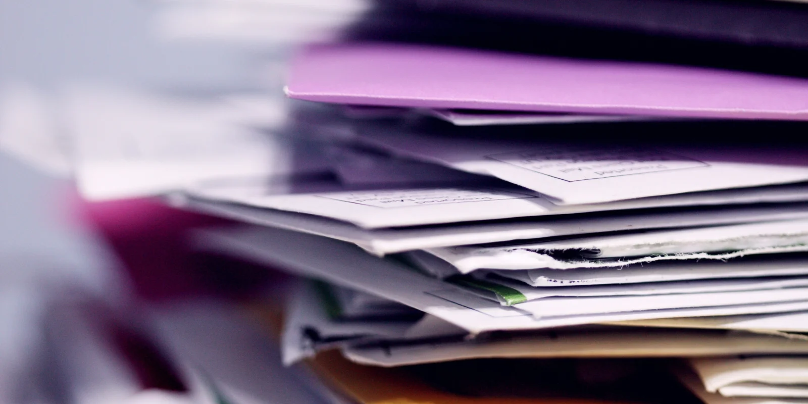 A stack of papers and folders, blurred background.