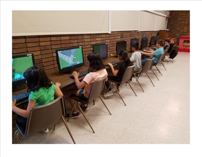 May contain: person, child, female, girl, chair, furniture, architecture, building, school, people, computer hardware, electronics, hardware, monitor, screen, clothing, footwear, shoe, classroom, indoors, room, computer, and computer keyboard