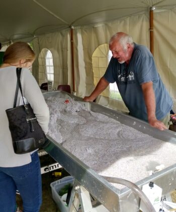 Two people examining a table filled with tiny stones, possibly a gem mining activity.
