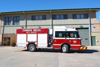 A red and white fire truck labeled "Timber Mesa Fire & Medical" parked in front of a building.
