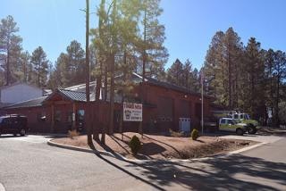 A fire station building with trees around and a fire truck parked outside.