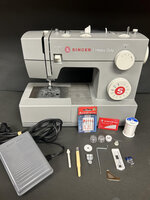 A sewing machine with various accessories, including a foot pedal, needles, thread, bobbins, and other sewing supplies.