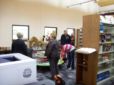 People browsing in a library with books, shelves, and a colorful display.