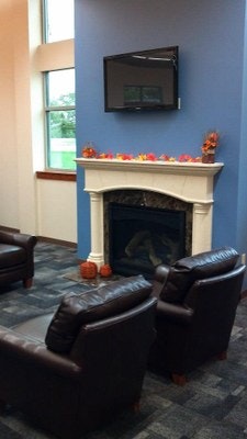 A cozy room with a fireplace, two armchairs, autumn decorations, and a TV mounted above the fireplace.