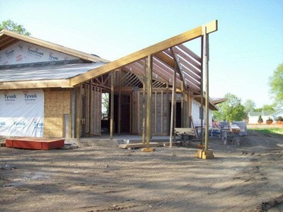 A house under construction with wooden framing and Tyvek wrap.