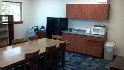 A small kitchenette with appliances and a table with chairs.